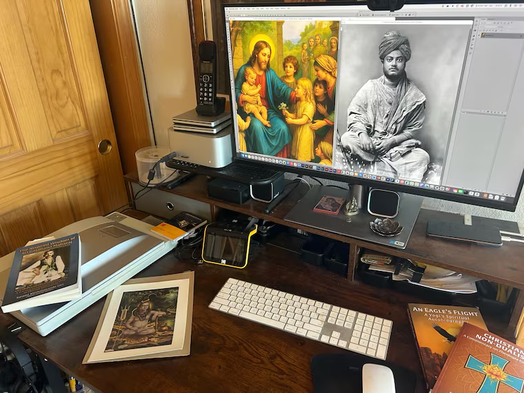 The monastery publishing workstation with books, scanner, keyboard, and sacred imagery